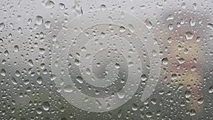 Strong rain water flushes against window glass and streaming down. Close-up. Raindrops on glass background in rainy