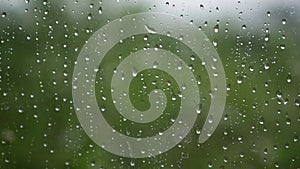 Strong rain water flushes against window glass and streaming down. Close-up. Raindrops on glass background in rainy