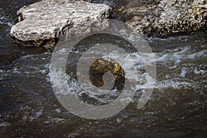 Strong river current, splash of water, waves and large stones.