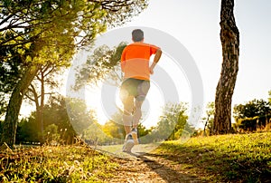 Strong runner training on rural track jogging at sunset in nature in cross country and sports