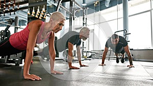 Strong senior couple doing plank at gym