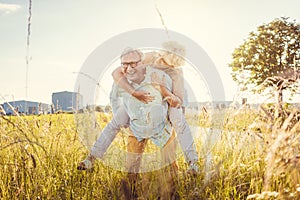 Strong senior man carrying his wife piggyback without back pain