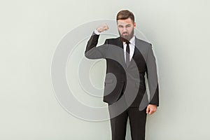 Strong, seriously bearded businessman showing muscle and looking