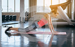 Strong and slim beginner woman doing push up exercises on yoga mat at gym