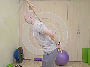 strong sport man holds a gymnastic stick on back. correct posture concept