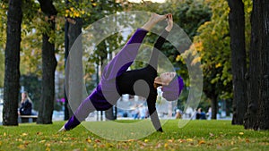 Strong sportive islamic girl in hijab yoga teacher woman stands in side plank on grass in park doing Ardhachandrasana