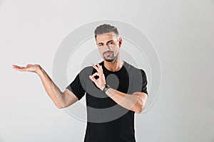 Strong sportsman standing isolated showing okay gesture.