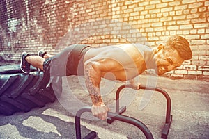 Strong sporty happy cheerful positive man doing press exercises holding plank outdoors