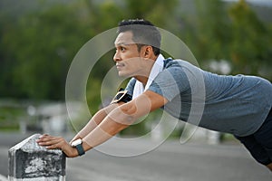 Strong sporty man in sports clothes and towel stretching, preparing for morning workout