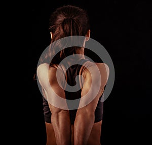 Strong sporty woman doing the arms and shoulders stretching exercise holding the hands in fist behind the back to relaxing back