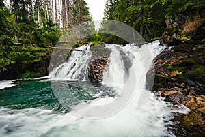 Strong stream of mountain waterfall in green forest - wide angle shot. Beautiful and power waterfall with turquoise water - stones