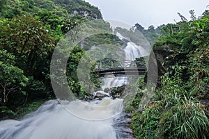Strong water flow and steel-arched bridge at Silver Waterfall Thac Bac waterfall in Sapa,Lao Cai province,North Vietnam.