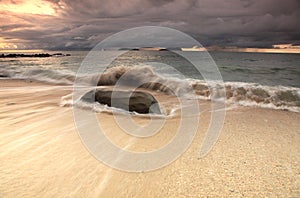Strong waves and big rock on the beach. photo