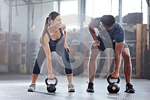 Strong, wellness couple doing kettlebell weight exercise, workout or training inside a gym. Happy sports people or