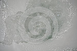 A strong whirlpool of water in the toilet. The water swirls in the toilet bowl. Water splashes.