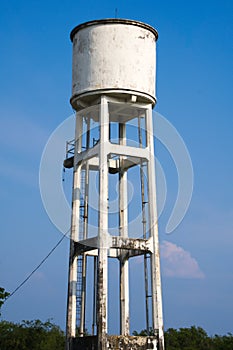 A strong white water tower, providing a rural area with fresh water, from high above, yet under an expansive blue sky.