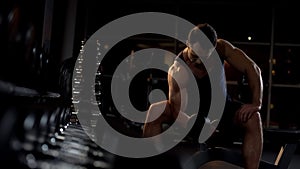 Strong-willed bodybuilder doing seated  dumbbell curl, evening workout