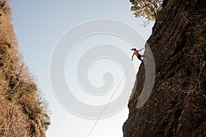 Strong woman equipped with a rope abseiling on the sloping rock