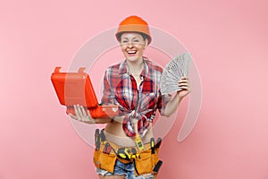 Strong woman in orange helmet, plaid shirt, denim shorts, kit tools belt full of instruments, toolbox, lots cash money