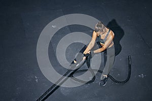 Strong woman pulling rope training in gym