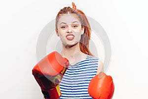 Strong woman in red boxing gloves and in a striped t-shirt front view light background