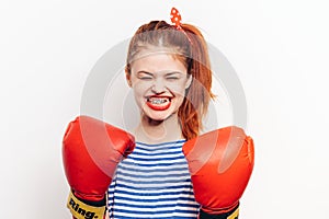 Strong woman in red boxing gloves and in a striped t-shirt front view light background