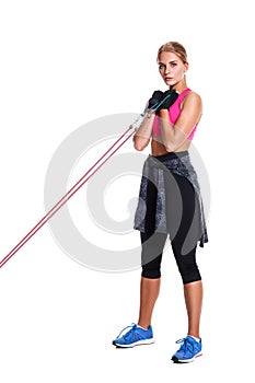 Strong woman using a resistance band in her exercise routine. Young woman performs fitness exercises on white background