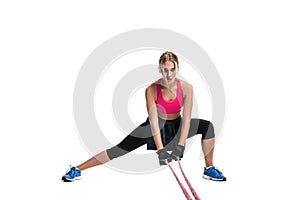 Strong woman using a resistance band in her exercise routine. Young woman performs fitness exercises on white background