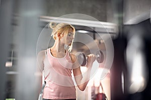 Strong woman doing exercises with dumbbells in gym