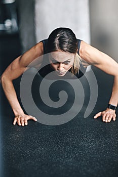 Strong women lift themselves up. an attractive young woman doing push ups in a gym.