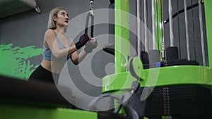 Strong young Asian woman exercising with pulldown machine in a fitness club, doing exercises in gym