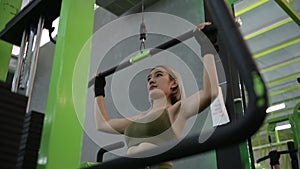 Strong young Asian woman exercising with pulldown machine in a fitness club, doing exercises in gym