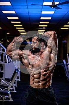 strong young athlete with beard showing sport physique in athletic workout gym