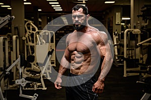 strong young bearded male with sport physique in athlete fitness gym during training workout