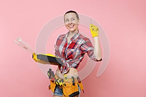 Strong young handyman woman in plaid shirt, denim shorts, kit tools belt full of different instruments holding toolbox