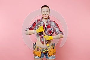 Strong young handyman woman wearing plaid shirt, denim shorts, kit tools belt full of different instruments hammer