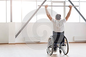 Strong young invalid exercising with weights in gym