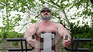 strong young male with beard training on outdoors sport arena during back muscle workout