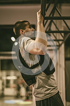 Young man doing pull ups in the gym