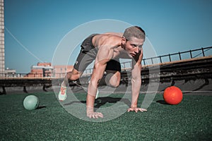 Strong young man doing sport exercises on the top of the buildig.