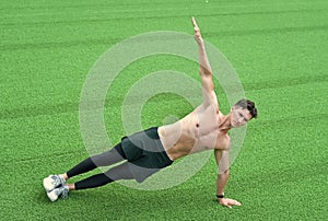 Strong young man doing sports outdoors. Man practicing yoga on grass. working out in fitness gym. do yoga in city. side