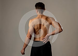 Strong young man suffering lower back pain in stress and bad posture