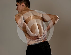 Strong young man suffering lower back pain in stress and bad posture