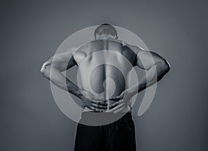 Strong young man suffering lower back pain in stress and bad posture