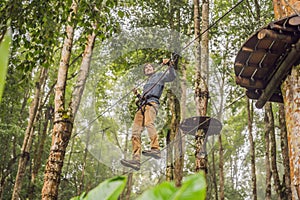 Strong young men in a rope park on the wood background