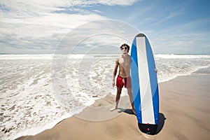 Strong young surf man portrait at the beach with a surfboard. Ba