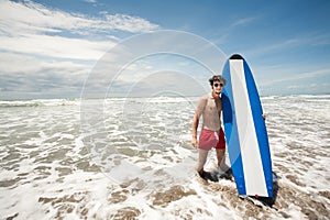 Strong young surf man portrait at the beach with a surfboard. Ba