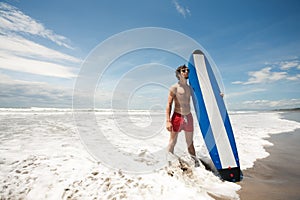 Strong young surf man portrait at the beach with a surfboard. Ba