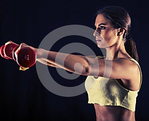 Strong young woman doing dumbbell front raises
