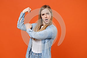 Strong young woman girl in casual denim clothes posing isolated on bright orange wall background studio portrait. People